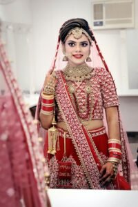 Stunning bride in traditional red and gold wedding attire, captured in a classic portrait style.